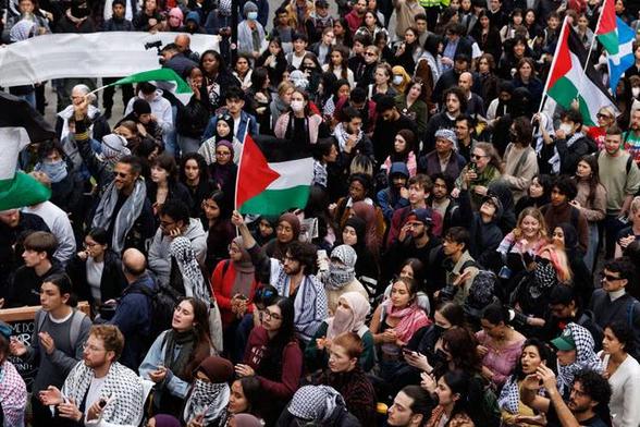 A crowd of students protest with Palestinian flags.