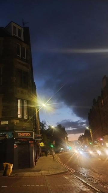 Dusk sky, darker blues above, shading to paper blue near the horizon, with a red tinge there from the just vanished sun, semi silhouetting the old Victorian tenements