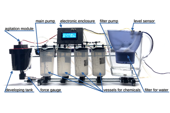 Picture of an OpenAutoLab machine with text clarifying what its main components are: agitation module, main pump, electronics, filter pump, level sensor, developing tank, force gauge, vessels for chemicals, filter for water.