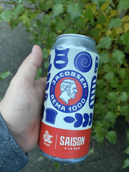 Ugens øl - Remas collab med Jacobsen og Jam&B ved navn Saison a La Bun med blå træsnit-agtige illustrationer på, holdes op foran en vortebirk