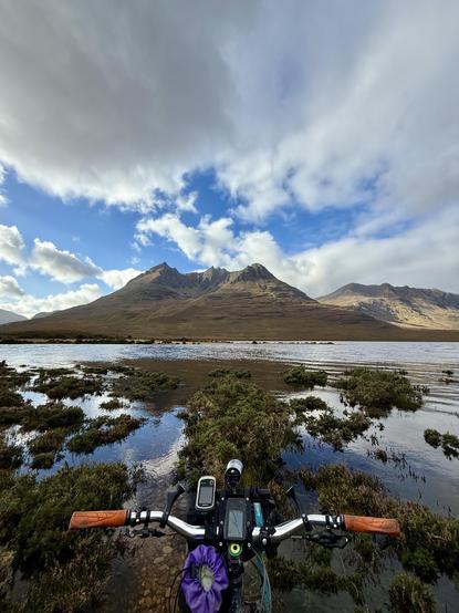View across river from behind handlebars with mountain on far side