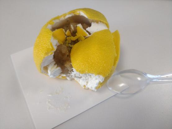 Photo d'un faux citron cassé, on voit une meringue blanche et de la compote à l'intérieur.