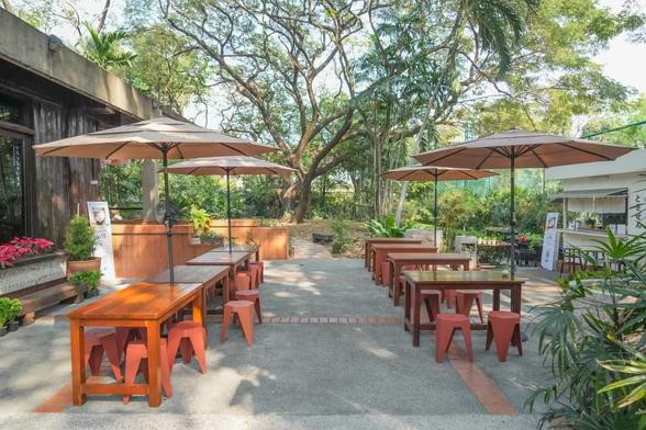 Outdoor seating area with tables and stools under umbrellas.