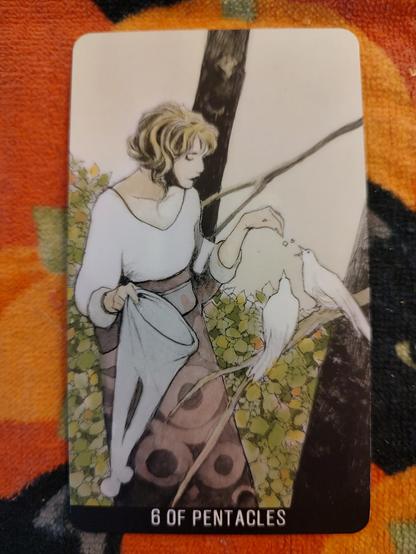 Card from the Joker Tarot deck. 
Six of Pentacles. 
A woman holding a large sack is feeding two birds on a tree branch.