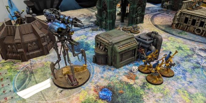 A miniature wargame in progress. A giant robot stares down a trio of space elf guardians.