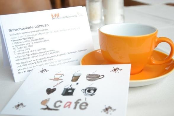 Eine Tasse auf einem Tisch und Zettel, die auf das Sprachencafé hinweisen.