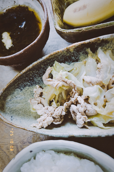 The pork dish, a cup of vinegared seaweed and a half of banana on a rectangle cup.