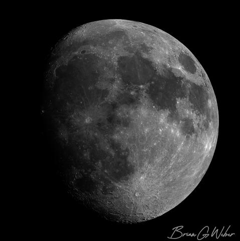 An 88% waxing moon with a single crater shining brightly out of the darkness on the left side. Depending on the sun angle, certain prominent craters may still be illuminated while the low-lying area around it is in shadow.