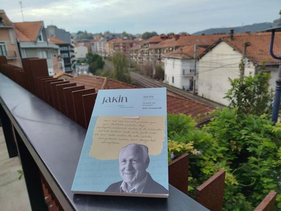 Jakin aldizkariak Joxe Azurmendiren omenez eginiko zenbaki bereziaren ale bat petril batean jarrita, atzean Errenteriako etxeak eta tipoaren trenbidea.