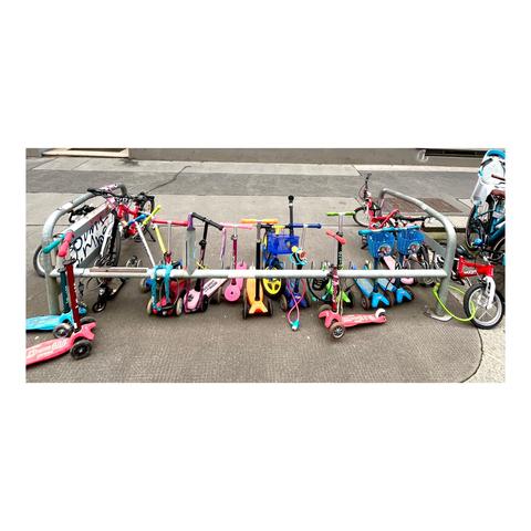 Eine Fahrradständerbucht, in der vor allem viele Tretroller in allmöglichen Farben abgestellt sind.