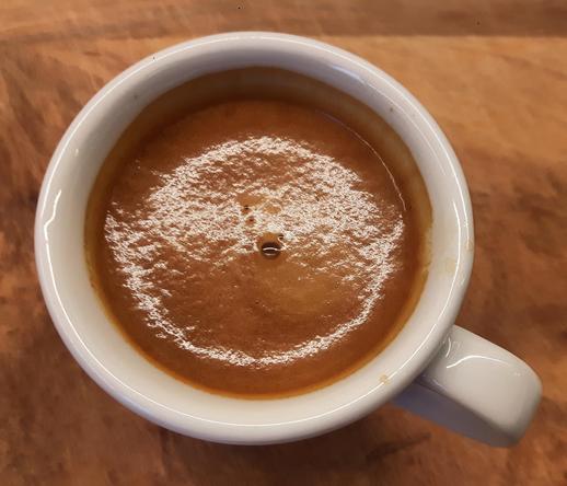 Eine Tasse Espresso mit dicker Crema steht auf einem Holzbrett.