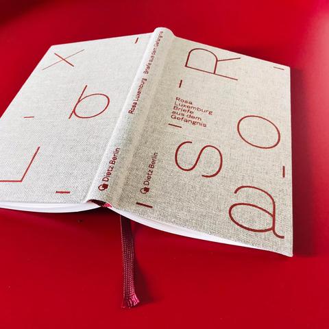 Aufgeschlagen mit Lesebändchen: das Buch „Rosa Luxemburg — Briefe aus dem Gefängnis“ als eine in grobes Leinen gebundene Edition mit groß geprägten Lettern auf Cover und Rücktitel