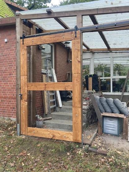 Picture of a wooden sliding door infront of roofed porch.