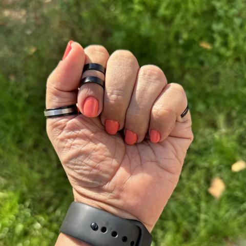 Mano izquierda cerrada mostrando las uñas de un color rosa anaranjado.