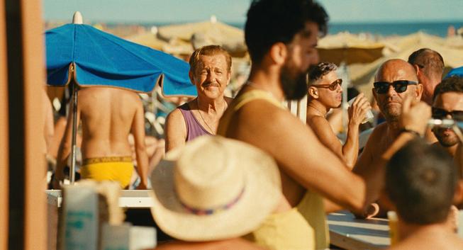 A man smile through a crowd on a beach