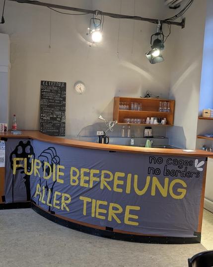 Die Theke bei der Essensausgabe. An ihr hängt ein Banner mit "Für die Befreiung aller Tiere"