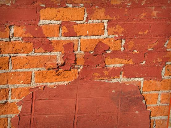 Painted brickwork with areas where the paint has peeled away
