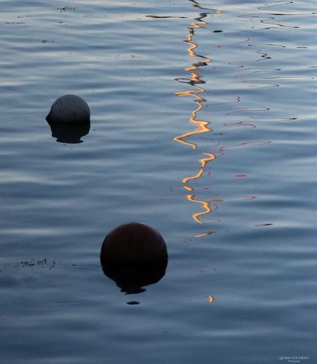 Water reflections produce an abstract image in black, blue, yellow and red.