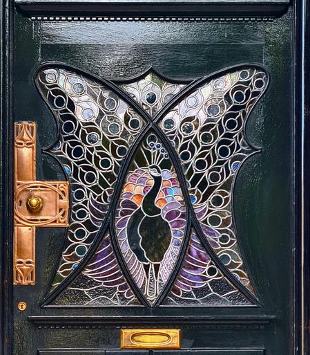 An Art Nouveau stained glaaa door window featuring a peacock.