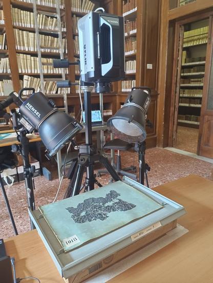 Immagine del laboratorio di analisi con attrezzature per la termografia attiva, inclusi scanner e luci, mentre un papiro carbonizzato è posizionato su un tavolo.