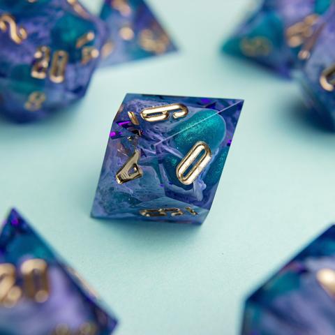 Zu sehen ist ein D10 in lila und türkisen Bloops die durch helle lila Schleier stechen.

Die Nummern sind in Gold geinked