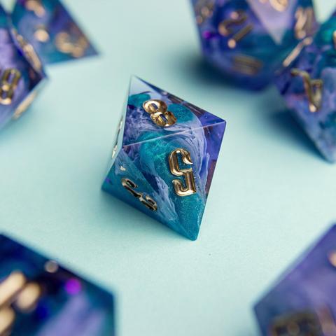 Zu sehen ist ein D8 in lila und türkisen Bloops die durch helle lila Schleier stechen.

Die Nummern sind in Gold geinked