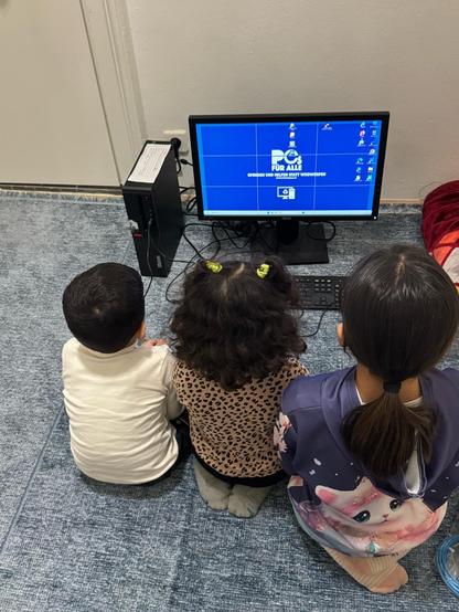 Gruppe Kinder am Boden vor einem PC sitzend