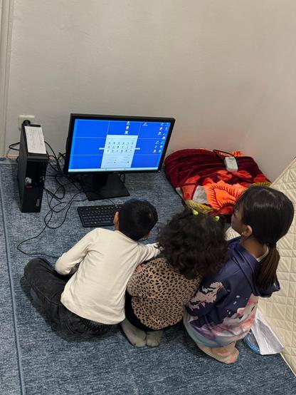 Gruppe Kinder am Boden vor einem PC sitzend