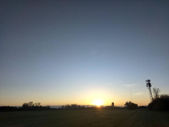 The sunrise shining the factory in the middle of the field