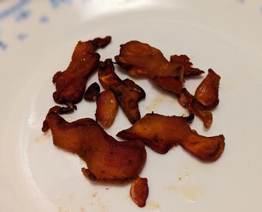Slices of fried mushroom on a plate. They have darkened to a warm red color.