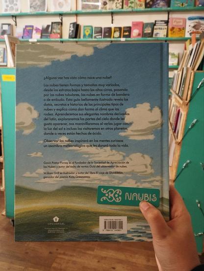 Contraportada del libro, siguiendo el paisaje de la portada (cielo azul, nubes blancas) y con el siguiente texto:
"¿Alguna vez has visto cómo nace una nube?
Las nubes tienen formas y tamaños muy variados, desde los estratos bajos hasta los altos cirros, pasando por las nubes tubulares, las nubes en forma de bandera y los tornados. Esta guía bellamente ilustrada revela los datos, secretos e historias de los principales tipos de nubes y explica cómo dan forma al clima que las rodea. Aprenderemos sus elegantes nombres derivados del latín, exploraremos las partes del cielo donde les gusta aparecer, nos maravillaremos al verlas jugar con la luz del Sol e incluso las visitaremos en otros planetas, donde a veces están hechas de ácido.
Observar las nubes para principiantes inspirará a las mentes curiosas un asombro meteorológico que les durará toda la vida."
