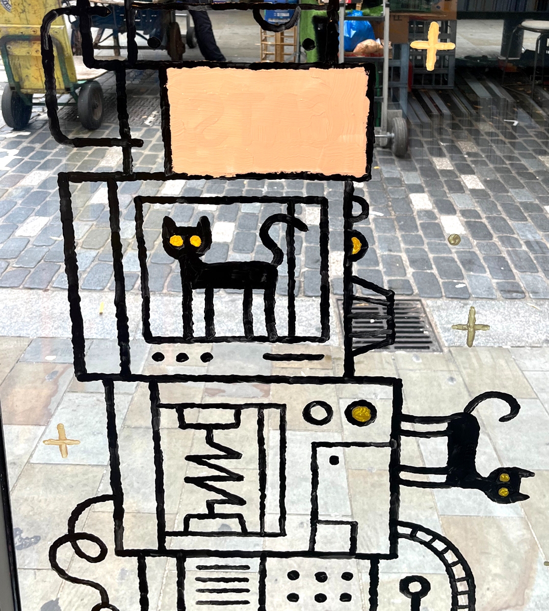 Cartoon cats and science machinery painted on a window of a comic shop. The text reads 'Physics for Cats: Science cartoons by Tom Gauld"