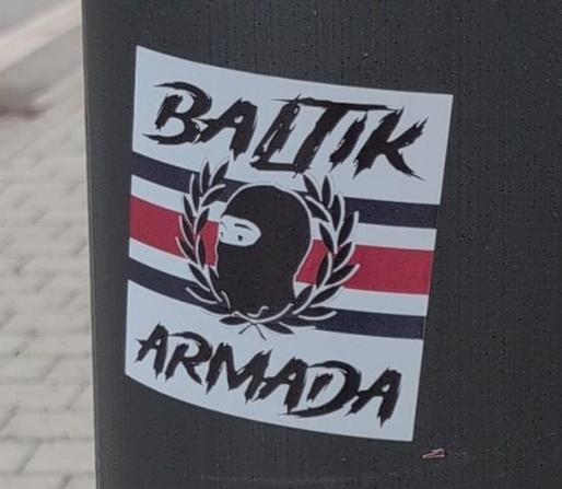 Aufkleber "Baltik Armada" im Fascho Stil, ein Kopf mit Hasskappe im Lorbeerkranz vor einer Flagge