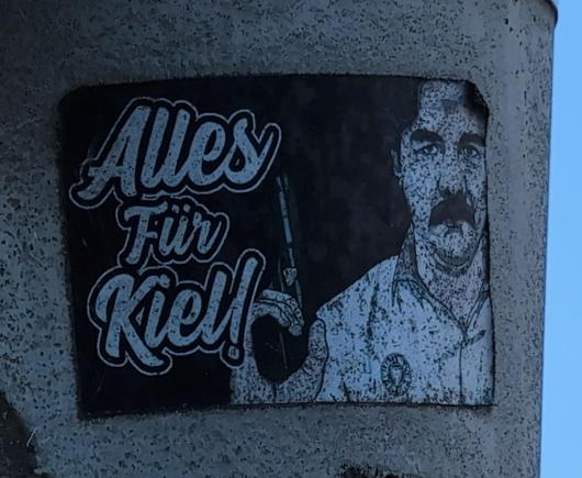Aufkleber "Alles für Kiel" 
Ein Mann mit Holstein Trikot hält eine Schusswaffe empor