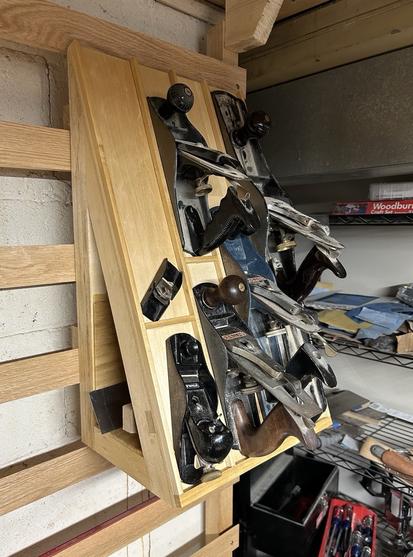 Several handplanes organized on a sloped rack hanging from some french cleats.