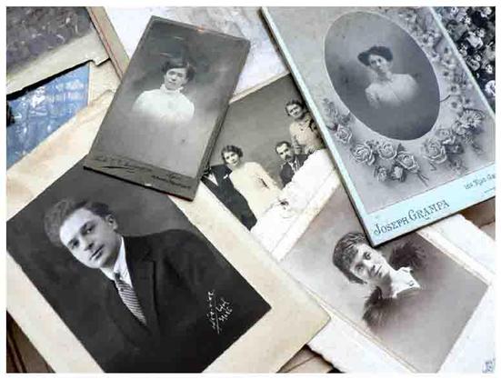 Une photo d'un ensemble de  9 portraits photographiques en noir et blanc avec une touche de couleur bleu-vert sur l'un des encadrements. Les photos sont  pêle-mêle . On remarque trois portraits de femme et celui d'un homme. et, partiellement cachée, une photo de mariage .
