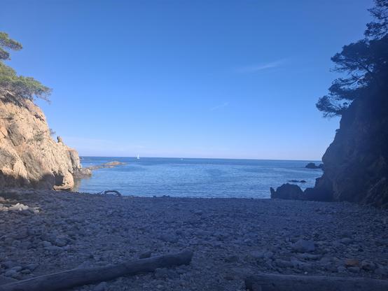 Blue water and rocky beach surrounded by cliffs.