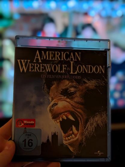 A close-up shot depicts a Bluray case held by a hand. The case is rectangular with a dark-colored cover featuring an image of a werewolf’s face, prominent with sharp teeth and intense eyes, set against a dark background with silhouetted buildings. The title “AMERICAN WEREWOLF IN LONDON” is displayed in large, bold, yellow lettering at the top of the case. Below the title is the text “EIN FILM VON LANDIS” in a smaller font.

Provided by @altbot, generated privately and locally using Gemma3:27b

🌱 Energy used: 0.113 Wh