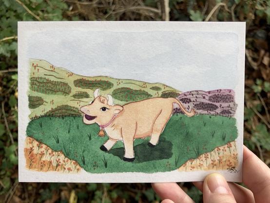 Art print of a watercolour painting of a light brown jersey cow standing in a beautiful meadow. She has a bell tied around her neck with a pretty pink ribbon and she looks very happy.