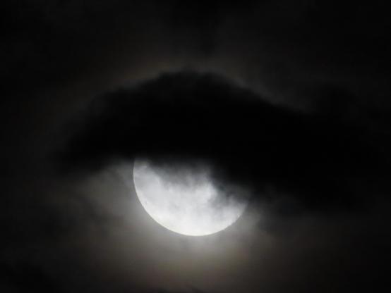 La pleine lune dans le ciel nuageux a l'air d'avoir des cheveux ou un bonnet.