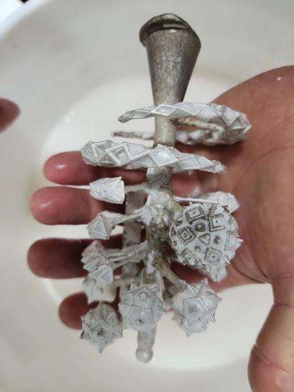 Hand holding a freshly cast sprue of sterling silver jewelry designs.