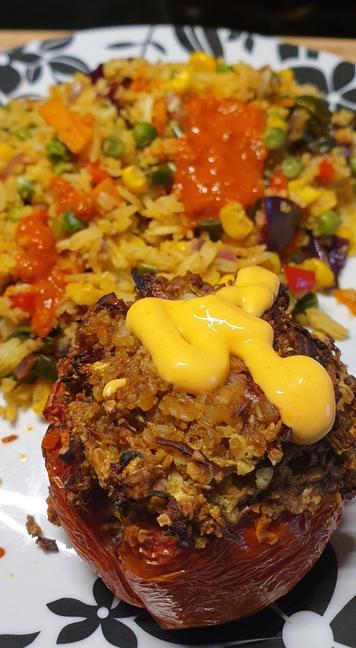 A plate with Walnut & oat stuffed roasted tomato and vegetable fried rice.