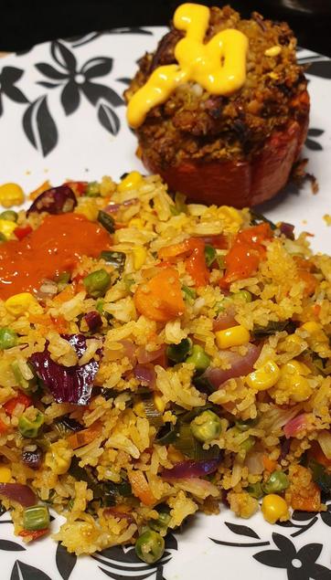 A plate with Walnut & oat stuffed roasted tomato and vegetable fried rice.
