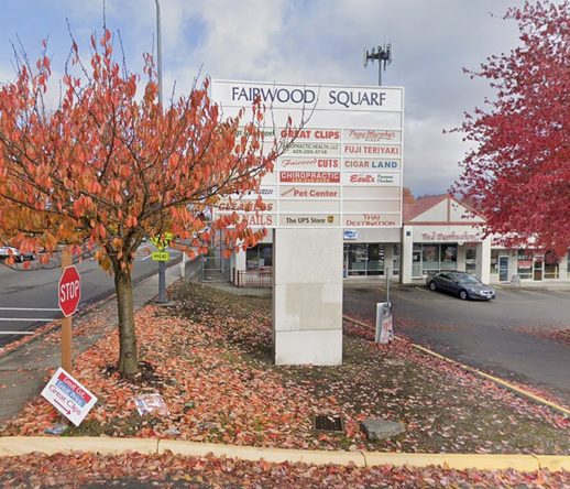 The sign for a strip-mall named "Fairwood Square", listing several business names, surrounded by a couple of fall-colored trees beside a road. You guessed it: "Fairwood Squarf".
