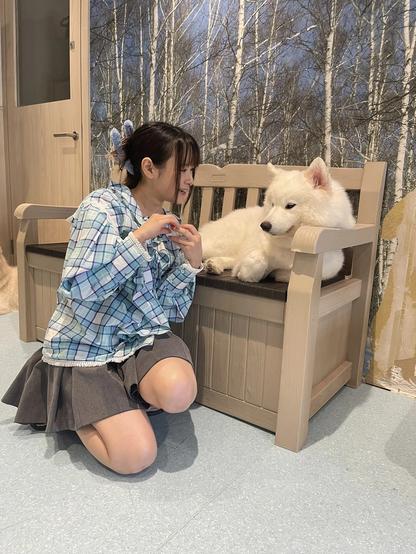 A woman looking at a dog that is lying on a bench.