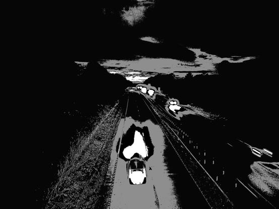 Black and white photo looking down at vehicles on the big road. Night time now.