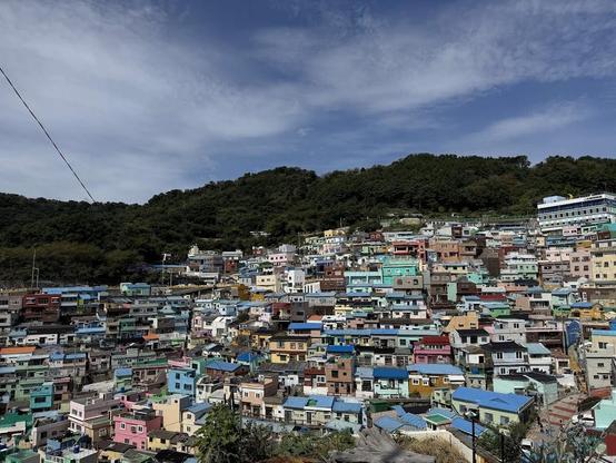 Colorful houses cascade down a hillside under a partly cloudy sky.