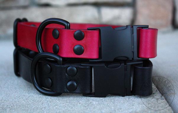 Two leather collars stacked on top of each other. The top is red with black hardware, and the bottom is black with black hardware. Both have a side-release buckle, D-ring, and adjustable slider