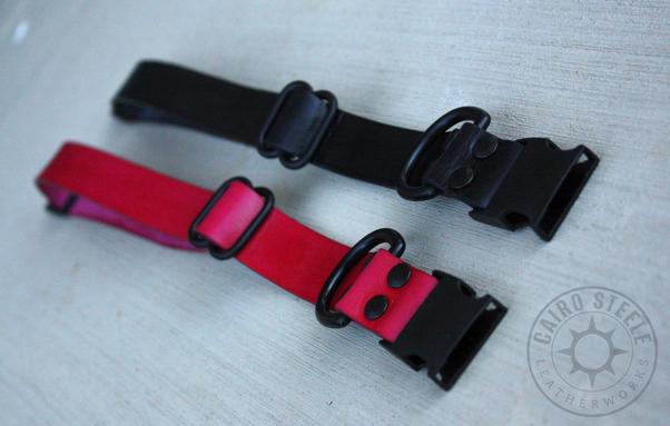 The two collars, unbuckled and laid flat, viewed at an angle from the end with the D-ring