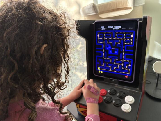 Over the shoulder photo of my 6yo daughter playing Pac Man running Mame on an iPad in an iCade cabinet